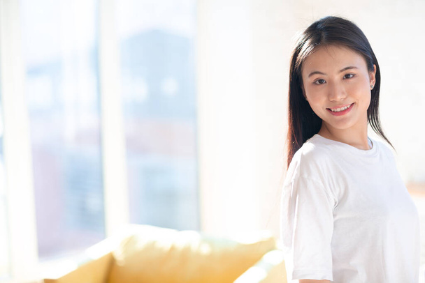 Portrait de souriant asiatique femme sur appartement fond intérieur - Photo, image