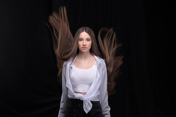 Beautiful brunette with long flying hair on a dark background. - Photo, Image