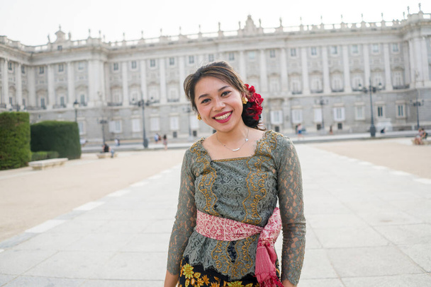 young happy Indonesian woman from Bali having vacation in Europe - beautiful and cheerful Balinese tourist girl in traditional outfit touring in the city enjoying holidays - Photo, image