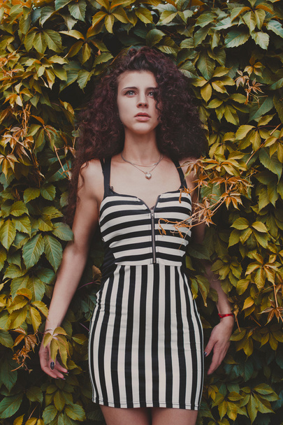 Fashion and beautiful young woman in a green wall of leaves - 写真・画像