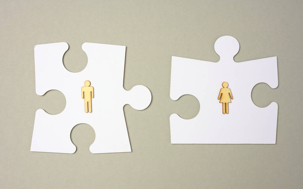 white puzzles and wooden men on a gray background. Recruitment concept, team compatibility, individuality. Couple compatibility in the family - Photo, Image