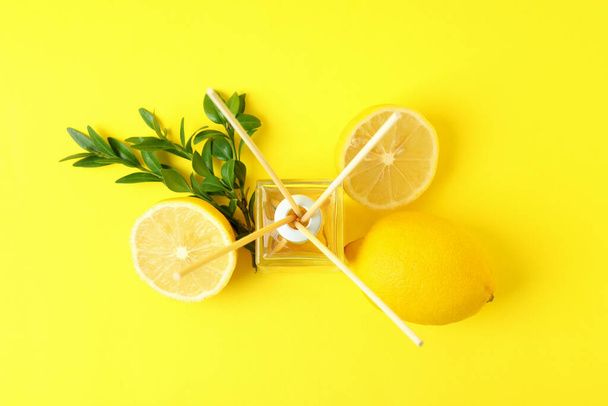 Diffuser, lemons and leaves on yellow background - Photo, Image