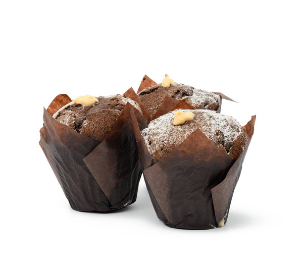 magdalenas de chocolate al horno con crema envuelta en papel marrón aislado sobre fondo blanco - Foto, Imagen