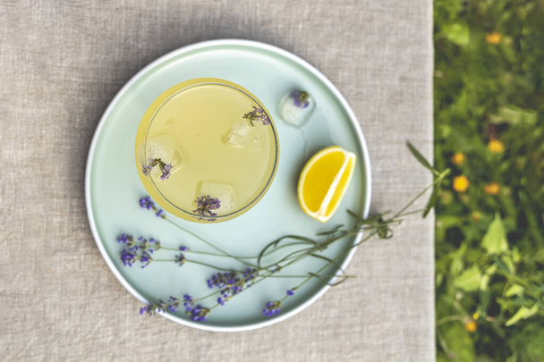 Top view Pompadour üveg levendula limonádé kocka jéggel és levendula virágokkal. Asztal a nyári kertben. - Fotó, kép