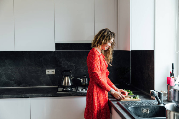 bela dona de casa mulher prepara uma salada de legumes na cozinha - Foto, Imagem