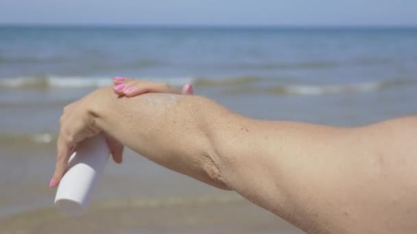 Kobieta stosowania ochrony przeciwsłonecznej balsam na jej ramieniu - Materiał filmowy, wideo