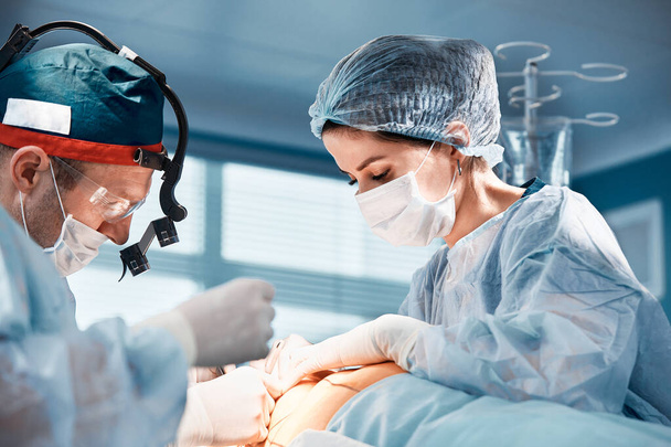 Close-up van chirurgen in de operatiekamer tijdens de operatie.Moderne geneeskunde, Medische medewerkers tijdens de Covid19 coronavirus pandemie vechten en redden levens. - Foto, afbeelding