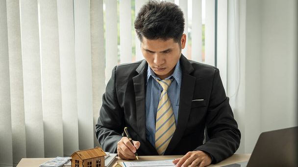 Businessman's hands calculate interest, taxes and profits to invest in real estate and home purchase real estate agent at office job with laptop. - 写真・画像