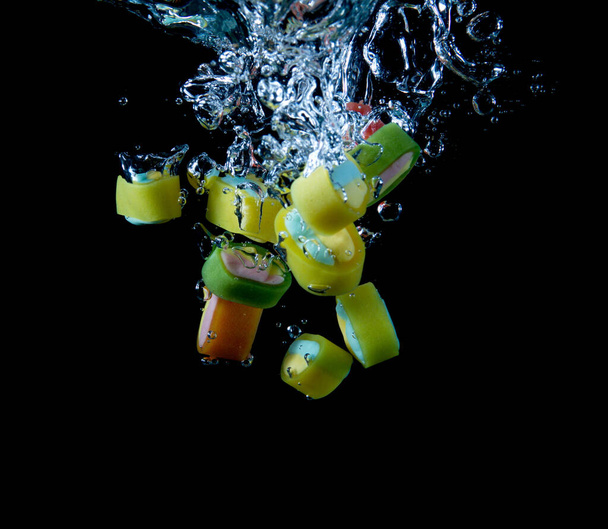 multicolored candies splashing into water on black background - Fotografie, Obrázek