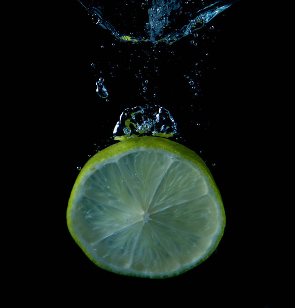 close-up view of lime falling into water isolated on black background - Zdjęcie, obraz