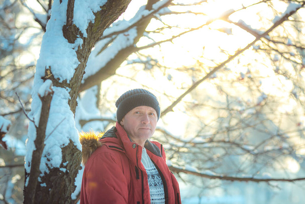 Portrait of a man on a snowy day in the forest. The guy in winter sportswear. - Valokuva, kuva