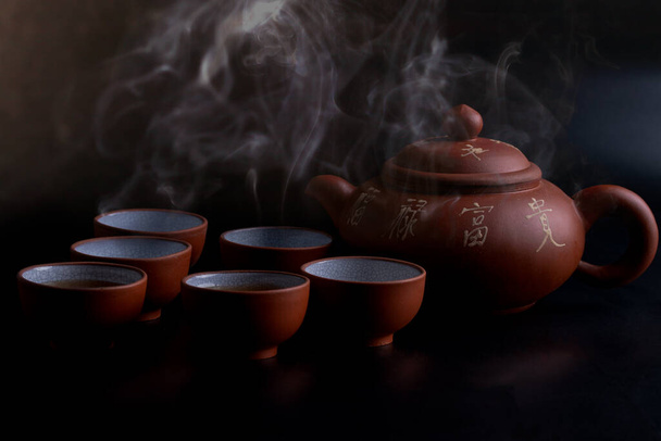Teiera marrone e vetro da tè su sfondo nero - Foto, immagini