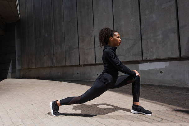 Side view of african american sportswoman stretching outdoors  - Zdjęcie, obraz