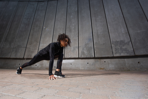 Low angle view of african american woman standing in starting pose before run  - Foto, afbeelding