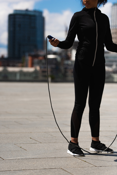 Cropped view of african american sportswoman holding jump rope on urban street  - Foto, Imagem