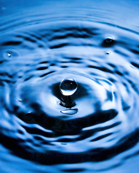 A drop of water and splashes with blurry waves on it. - Photo, Image