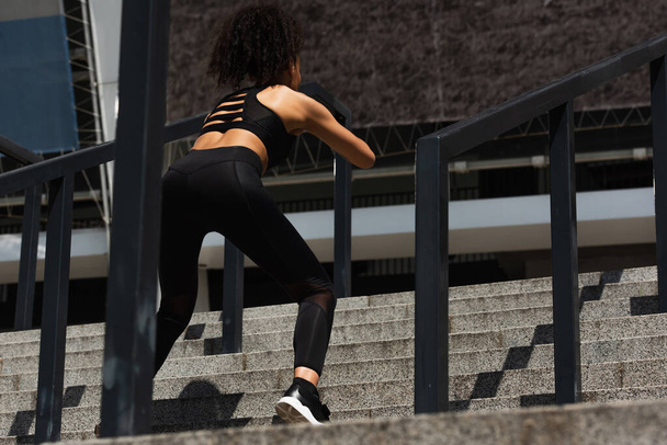 Back view of african american woman exercising on stairs near railing  - Foto, Bild
