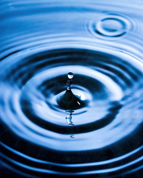 A drop of water and splashes with blurry waves on it. - Photo, Image