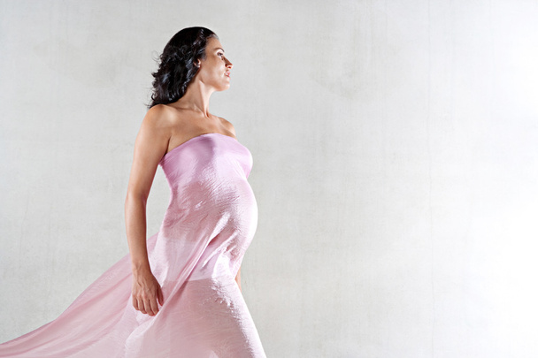 Mujer embarazada fuerte envuelta en seda rosa
 - Foto, Imagen