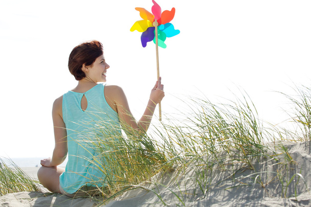 Жінка тримає барвисту іграшку вітряної млини
 - Фото, зображення