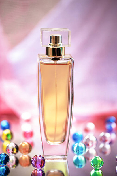 Bottiglia di profumo con palline di vetro colorato su uno sfondo chiaro. Profumi, cosmetici, una collezione di profumi. - Foto, immagini