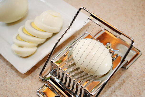 Schneiden eines gekochten Eies mit einem Teller im Hintergrund - Foto, Bild