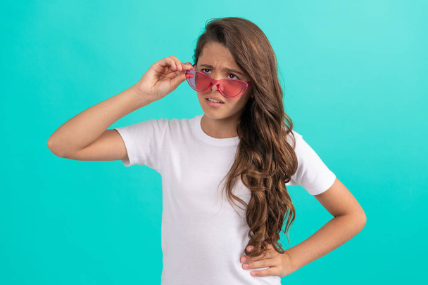 unhappy kid long curly hair in sunglasses casual style on blue background, fashion style - Photo, Image