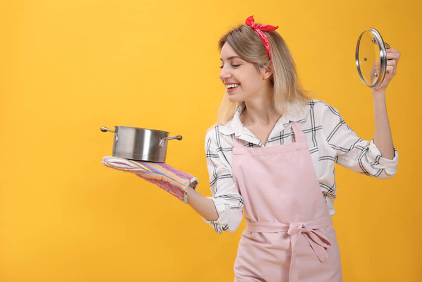 Young housewife with pot on yellow background - Fotografie, Obrázek