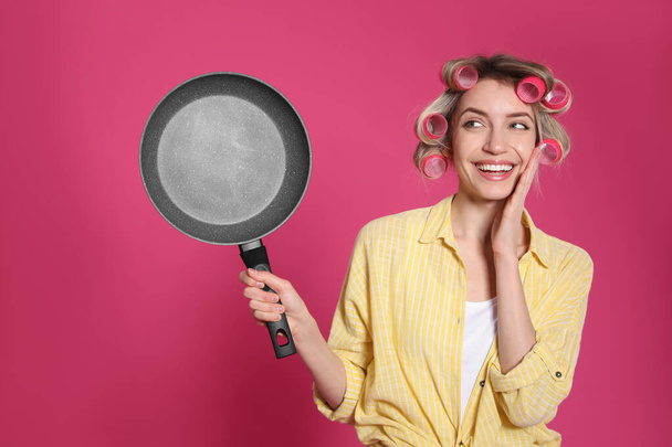 Young housewife with frying pan on pink background - Photo, image