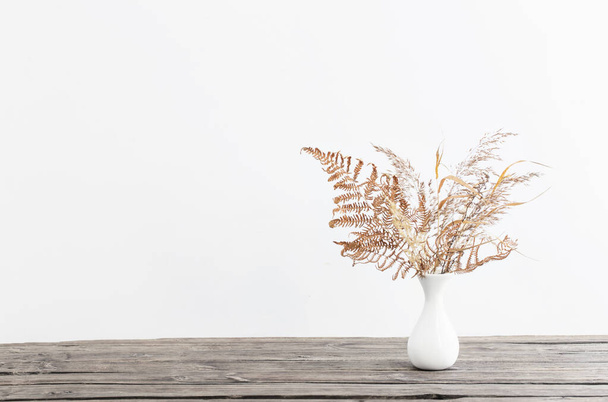 dried flowers in vase on wooden table on white background - Foto, imagen