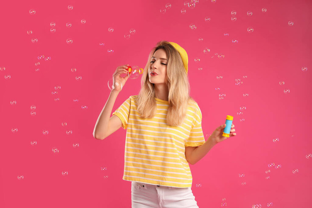 Young woman blowing soap bubbles on pink background - Photo, Image