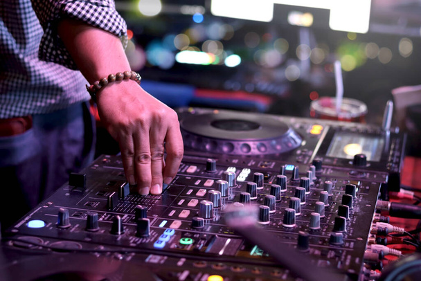 DJ mano tocando set en vivo y mezclando música en el controlador de mesa giratoria mesa de mezclas en el escenario en el club nocturno, música fiesta en la playa festiva y concepto de vida nocturna. - Foto, Imagen