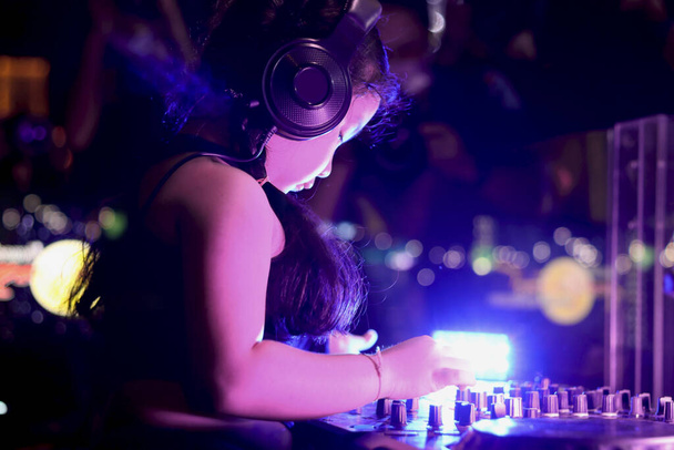 Meisje DJ spelen live set en mixen van muziek op controller draaitafel console mixbureau op het podium in de nachtclub, muziek beach party festiva en nachtleven concept. - Foto, afbeelding