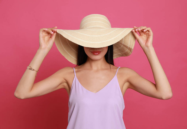 Beautiful young woman with straw hat on pink background - Fotografie, Obrázek