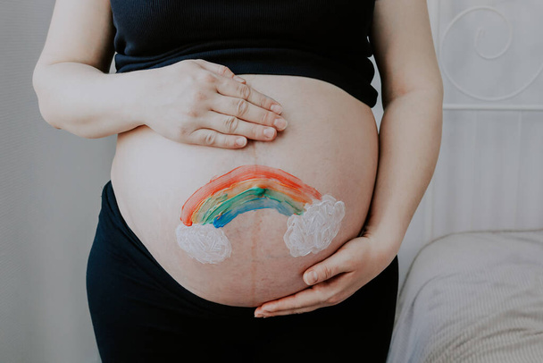 Egy terhes nő tartja a hasát egy ívet húzott a festék, közeli oldalnézetből. - Fotó, kép
