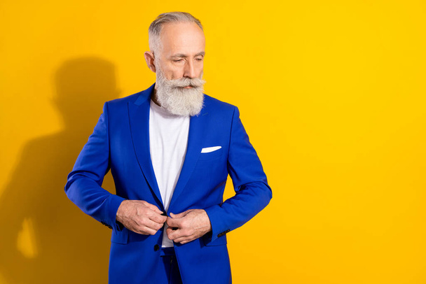 Photo of strict grey beard old man look empty space wear blue jacket isolated on vivid yellow color background - Fotoğraf, Görsel