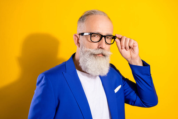 Portrait of calm aged person hand touch glasses look interested camera isolated on yellow color background - Foto, Bild