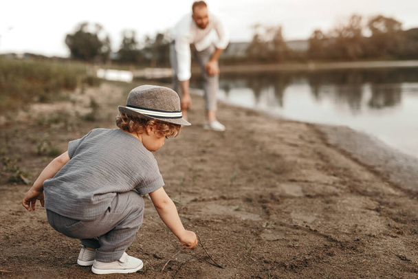 Little kid with father playing on river shore - Fotoğraf, Görsel