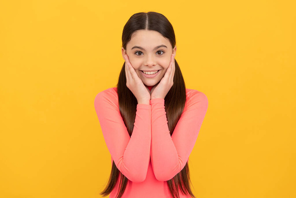 happy teen girl with long hair on yellow background, skincare - Fotoğraf, Görsel