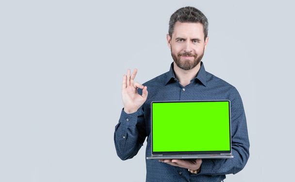 uomo barbuto sorridente mostrando schermo portatile verde per la presentazione video, spazio copia, ok - Foto, immagini