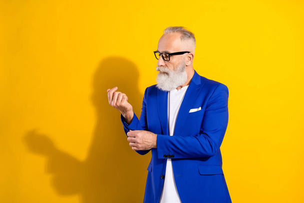 Photo of charming luxurious old man fix sleeve wear glasses blue jacket isolated on yellow color background - Foto, imagen