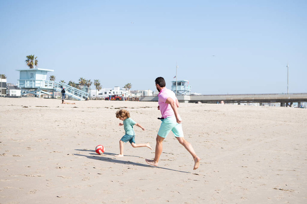 счастливый отец и сын играют в футбол весело провести лето песчаный пляж семейного отдыха, воспитания - Фото, изображение