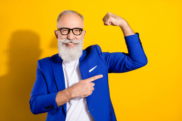 Portrait of attractive imposing cheerful man demonstrating muscles isolated over bright yellow color background - Φωτογραφία, εικόνα