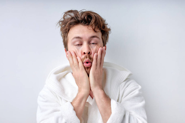 Handsome funny guy in bathrobe touching face, in the morning, cant wake up - Foto, imagen