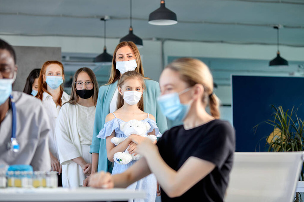 Vaccination against flu or Covid-19 virus. Scared Child Girl With Toy Standing In Queue - Фото, зображення