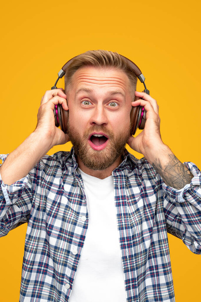 Astonished bearded man listening to music - Foto, imagen