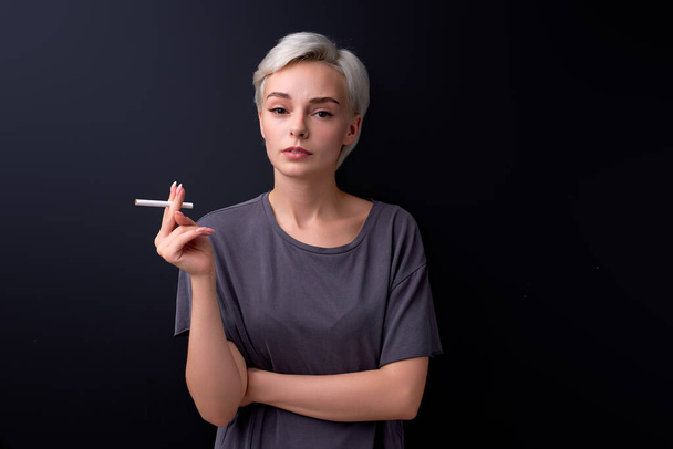 Serious woman holding Cigarette in hands. Cigarettes or tobacco, isolated on black - Photo, Image