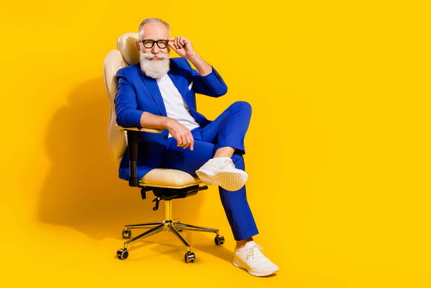 Full length body size photo of man with white beard smiling sitting inoffice chair isolated vivid yellow color background - Valokuva, kuva
