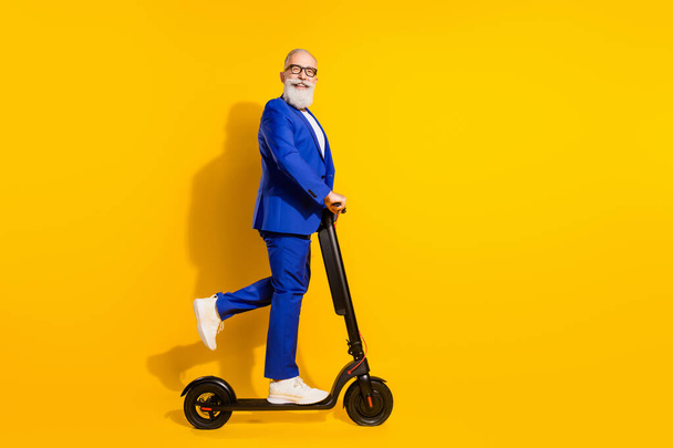Full length body size profile side view of nice cheerful chic man riding scooter having fun isolated over bright yellow color background - Фото, зображення