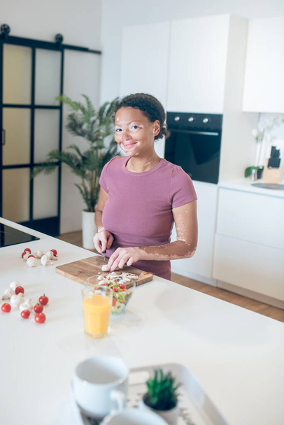 A dark-skinned woman cooking in the kitchen and cutting vegetables - Foto, Bild